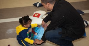A father helps his young child read a book at Mosaic's "Father and Child Day."