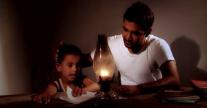 Father and child read together by candlelight in still from World Vision Lanka's MenCare TV spot.
