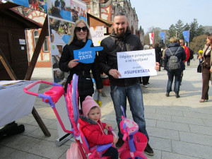 A father holds a sign that reads: "I raise by example, not by violence."