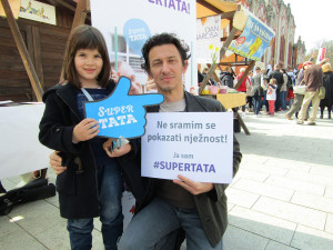 A father holds a sign that reads: "I am not ashamed to show tenderness."