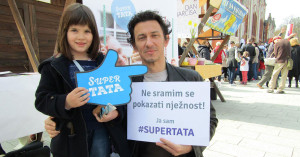 A father holds a sign that reads: "I am not ashamed to show tenderness."
