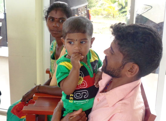 A father holds a child in his arms in Watawala ADP, Sri Lanka.