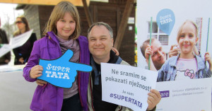 A father in Croatia holds a sign that reads: "I am not ashamed to show tenderness."