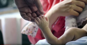 Still of an adult and a baby holding hands from the film "Father Is Not A Visitor."