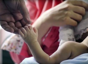 Still of an adult and a baby holding hands from the film "Father Is Not A Visitor."