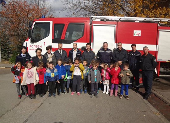 Students and fathers stand in front of a fire truck.