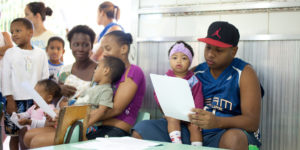 Adults and children sit inside. Photo by Beto Pêgo for Instituto Equimundo.