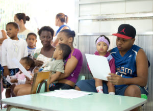 Adults and children sit inside. Photo by Beto Pêgo for Instituto Equimundo.