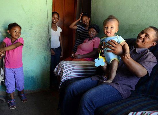 A father plays with his children at home in South Africa