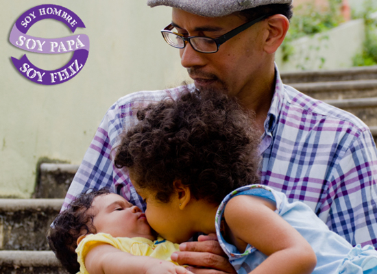 A father holds a baby as a another child gives the baby a kiss.