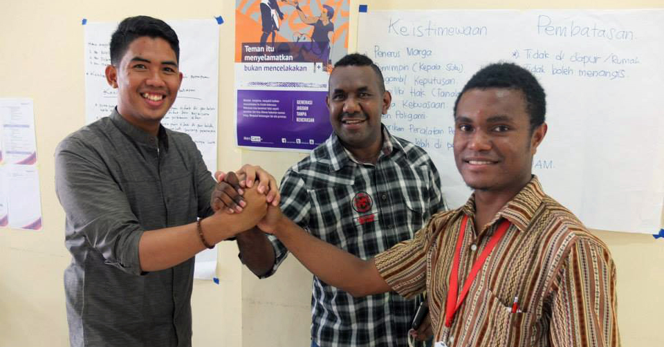 Three young men hold hands at a MenCare+ Indonesia facilitator training in Papua.