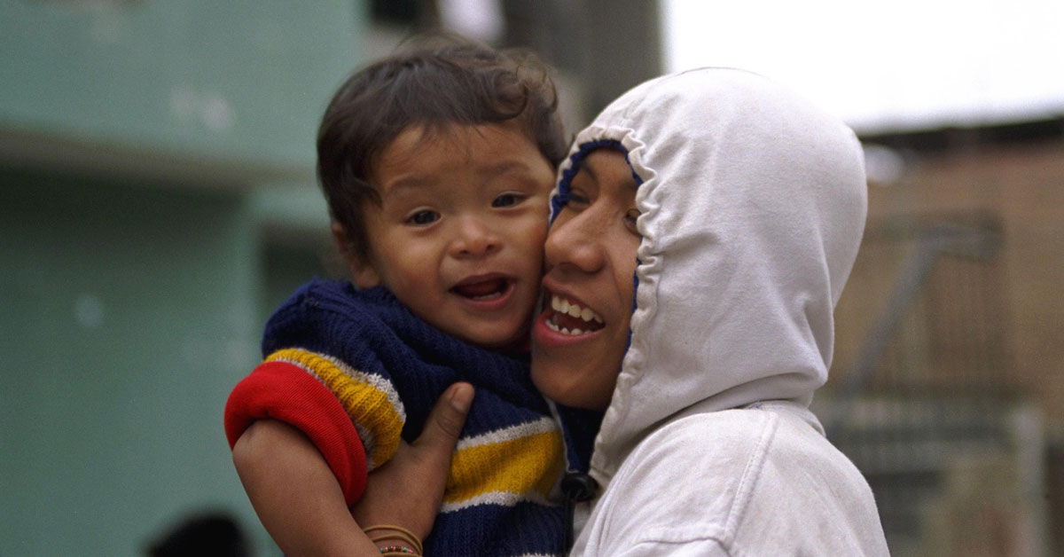 A joyful father holds his smiling, toddler son close in Peru.