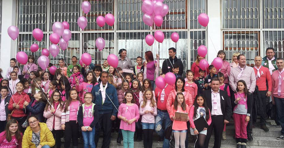 Children and adults dressed in pink hold pink balloons.