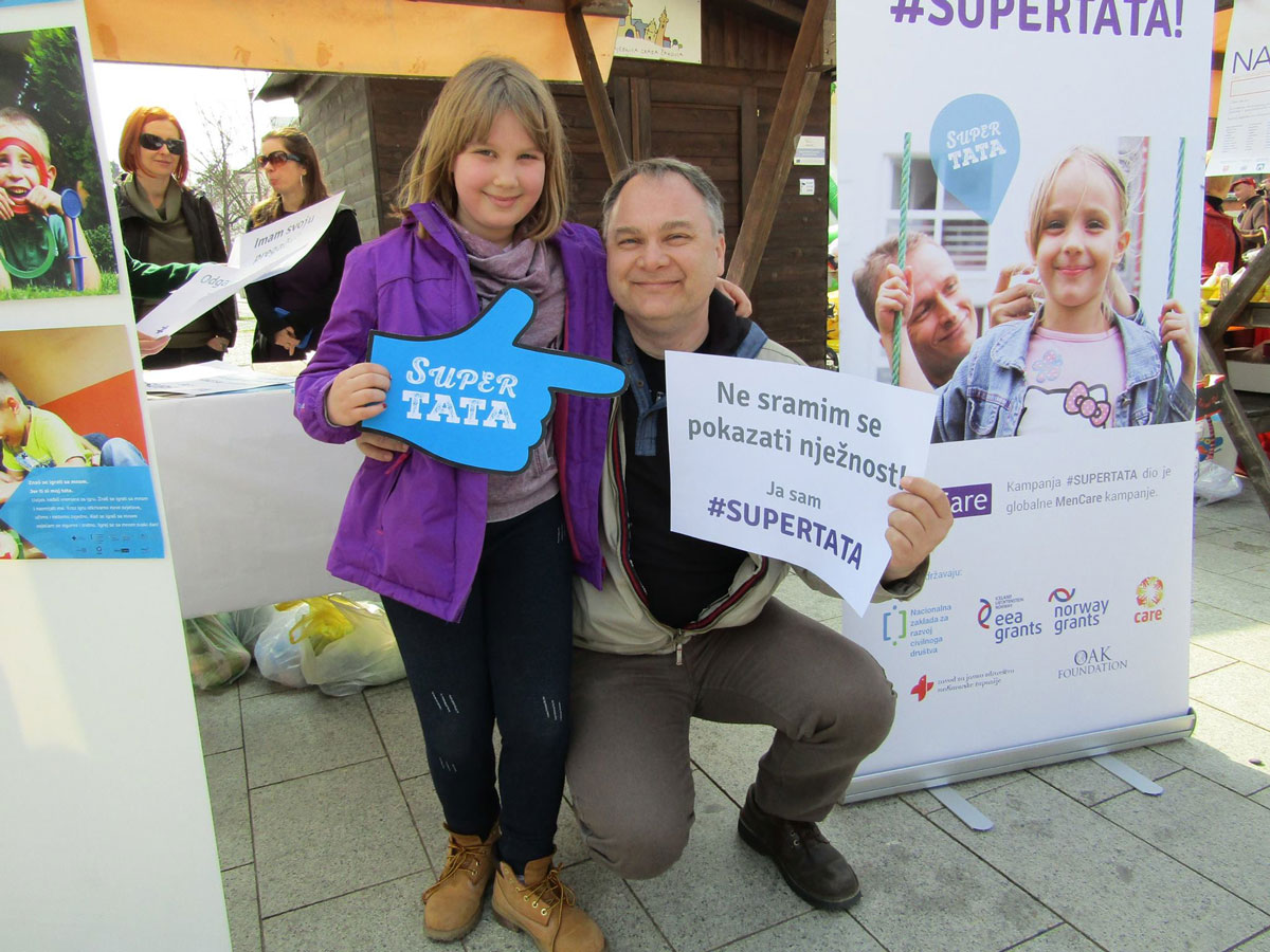 A father holds a sign that reads: “I am not ashamed to show tenderness."