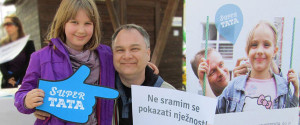 A father in Croatia holds a sign that reads: "I am not ashamed to show tenderness."