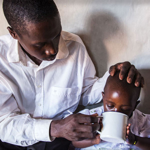 A man feeds his daughter in Rwanda.