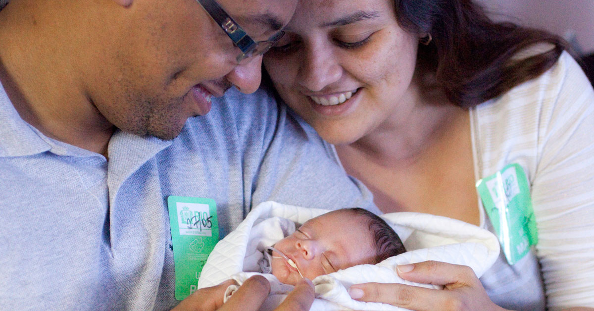 A mother and father hold their newborn baby in Brazil.