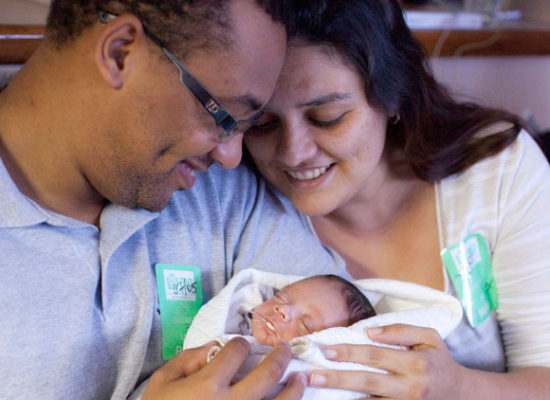 A mother and father hold their newborn baby in Brazil.