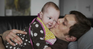 A father holds a baby. Photo: Johan Bävman / mencare.swiss.