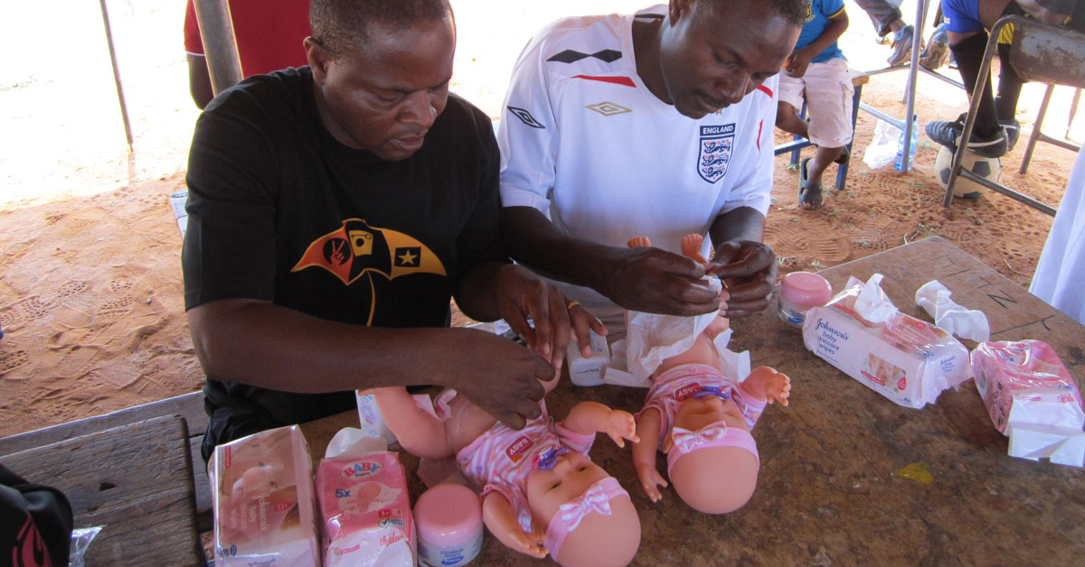 Two men learn to change diapers in South Africa.