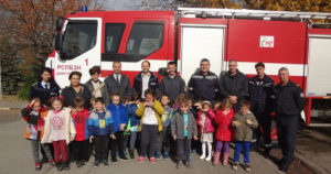 Students and fathers stand in front of a fire truck.