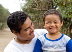 A father looks at his smiling son.
