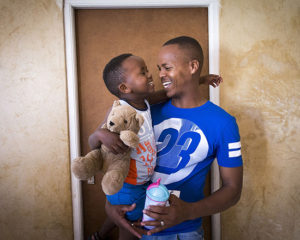 A smiling father holding his smiling son.