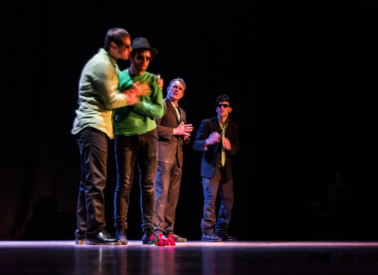 Four men on a stage, with one man embracing another.