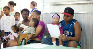 Adults and children sit inside. Photo by Beto Pêgo for Instituto Equimundo.