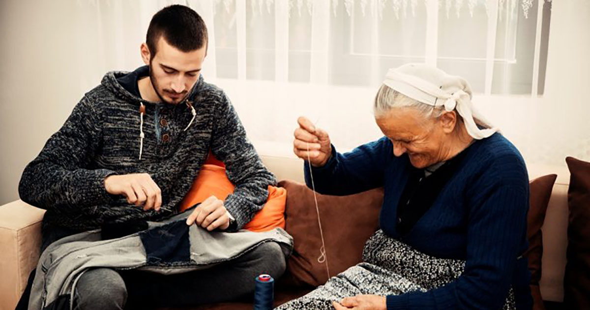 A young man and an older woman, sewing